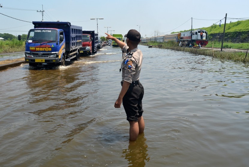 Polisi mengatur arus lalu lintas kendaraan yang melintasi genangan banjir di Jalan Raya Porong, Sidoarjo, Jawa Timur, Kamis (18/2).    (Antara/Umarul Faruq)