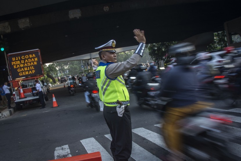 Polisi mengatur arus lalu lintas pada hari pertama uji coba perluasan kawasan ganjil genap di persimpangan Pancoran, Jakarta, Senin (2/7).