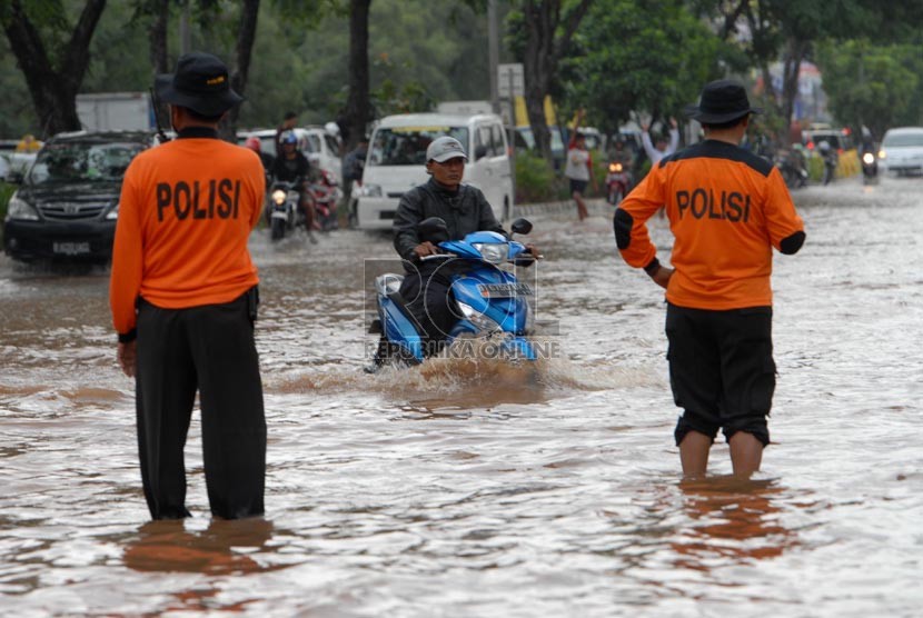   Polisi mengatur lalu lintas di ruas jalan yang terendam banjir di Jalan Boulevard Barat, Kelapa Gading, Jakarta Utara, Jumat (17/1). (Republika/Rakhmawaty La'lang)