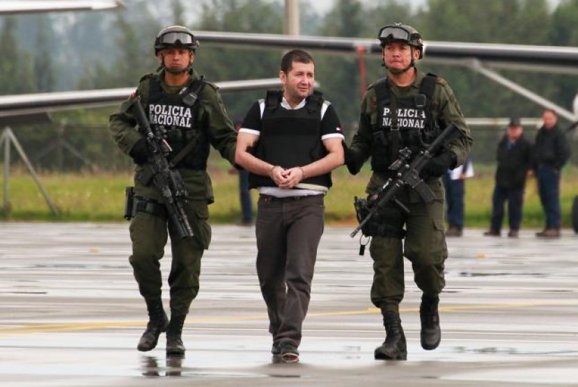 Polisi mengawal gembong narkoba Kolombia Daniel 'El Loco' Barrera sebelum diekstradisi ke Amerika Serikat, di sebuah bandara di Bogota pada 9 Juli 2013.