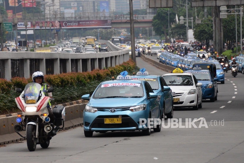 Polisi mengawal ribuan taksi saat meninggalkan aksi di depan DPR, Jakarta, Selasa (22/3).  (Republika/Yasin Habibi)