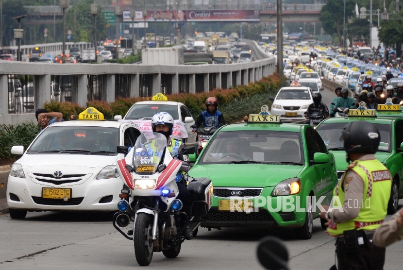Polisi mengawal ribuan taksi saat meninggalkan aksi di depan DPR, Jakarta, Selasa (22/3).