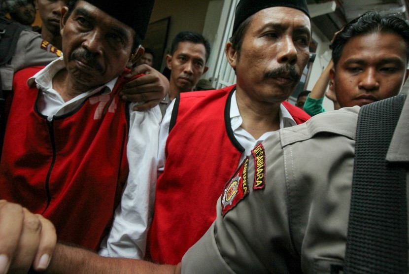 Polisi mengawal terdakwa kasus pembunuhan aktivis tambang pasir Lumajang Salim Kancil dan penganiayaan Tosan, Kepala Desa Selok Awar-Awar (non aktif) Hariyono (kedua kiri) dan Mad Dasir (kiri) usai mengikuti sidang putusan di Pengadilan Negeri Surabaya.