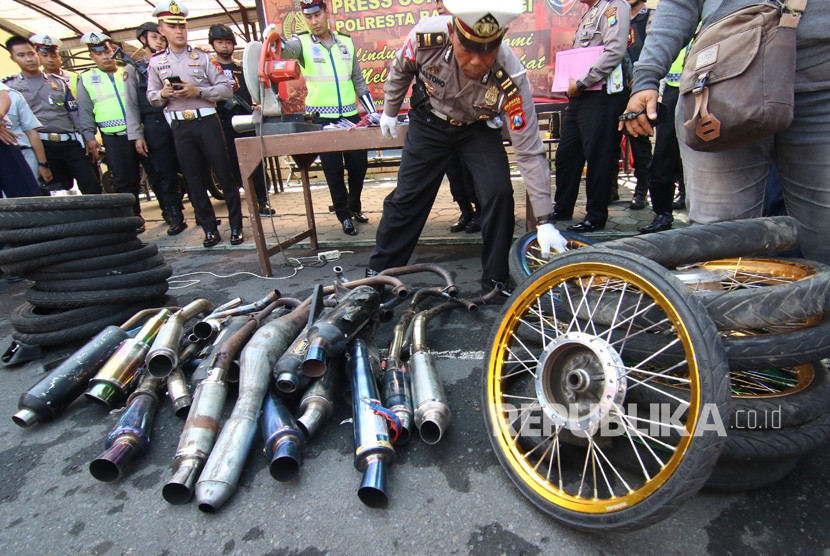 Polisi mengecek knalpot yang tidak memenuhi standard saat rilis hasil operasi balap liar, di Polresta, Banyuwangi, Jawa Timur, Rabu (22/1/2020).