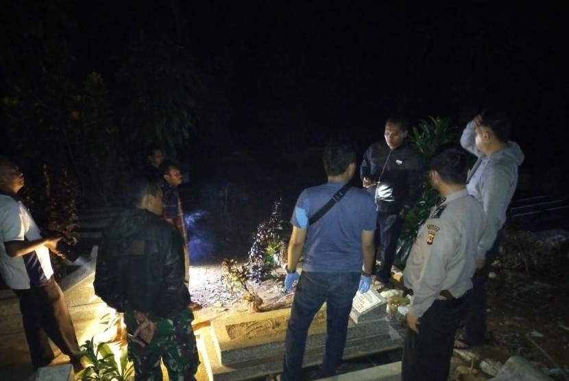 Polisi mengecek kondisi makam yang terbuka sebagian di TPU Kampung Pakemitan II, Desa Pakemitan, Kecamatan Cikatomas, Kabupaten Tasikmalaya, Jumat (8/11) malam. 