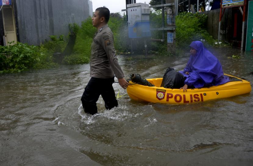 Polisi mengevakuasi seorang warga dari lokasi banjir menggunakan perahu karet di Kecamatan Somba Opu, Kabupaten Gowa, Sulawesi Selatan, Rabu (10/3/2021). Hujan dengan intensitas tinggi yang mengguyur Kabupaten Gowa dan juga dibukanya pintu air bendungan bili-bili membuat sungai yang berada di sekitar daerah tersebut meluap sehingga mengakibatkan sejumlah rumah dan jalan terendam banjir.