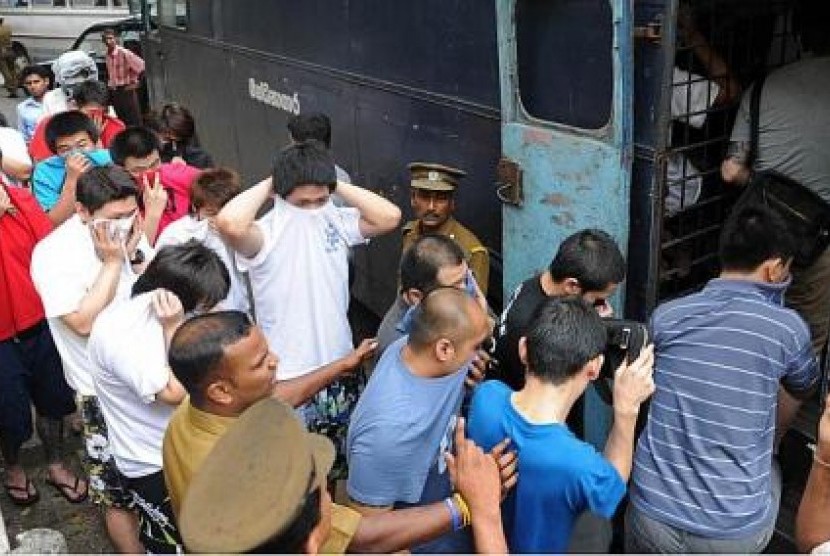 Polisi menggelandan ratusan warga Cina tersangka penipuan keuangan di Internet ke truk tahanan.