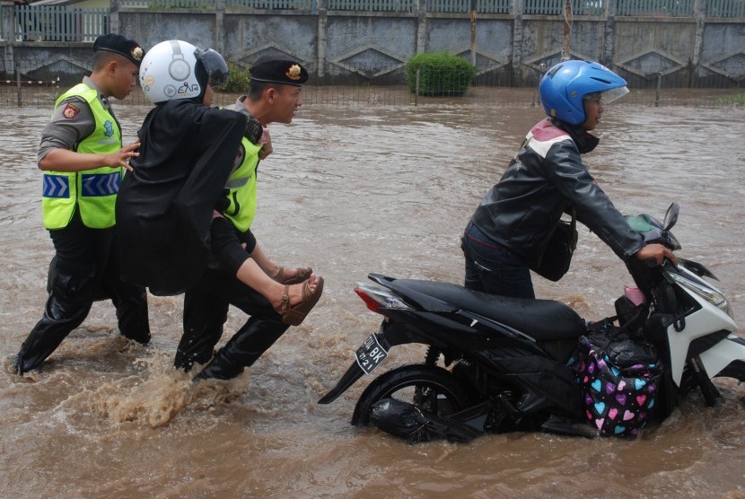 Polisi menggendong seorang ibu berusaha melintasi banjir di depan Pabrik Kahatex kawasan Rancaekek, Kabupaten Bandung, Jawa Barat, Selasa (1/11).