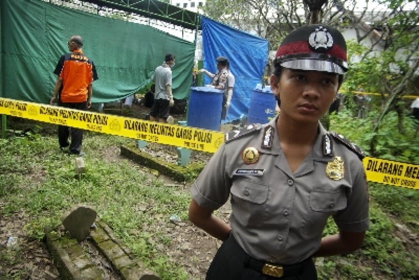 Polisi menjaga area makam saat otopsi mayat.