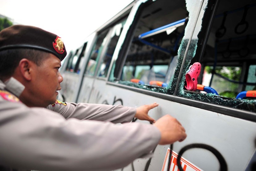 Polisi menjaga Bus Transjakarta yang dirusak massa di Jl Mampang Prapatan, Jakarta Selatan, Jumat (13/7).  (Yogi Ardhi/Republika)
