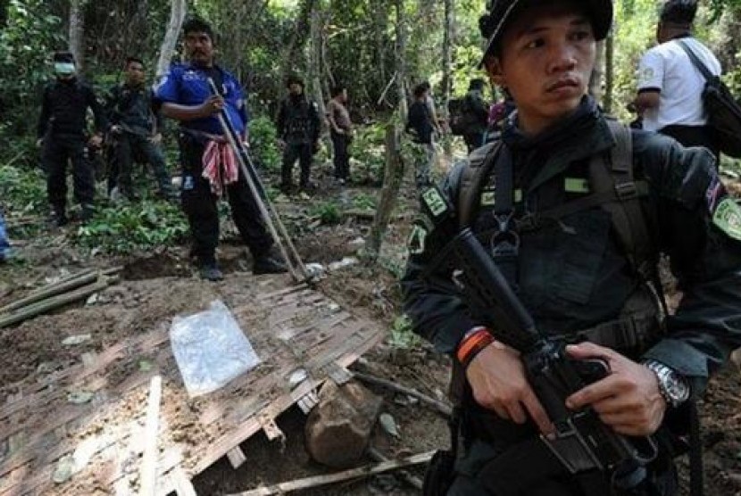 Polisi menjaga kuburan massal di perbatasan Malaysia dan Thailand.