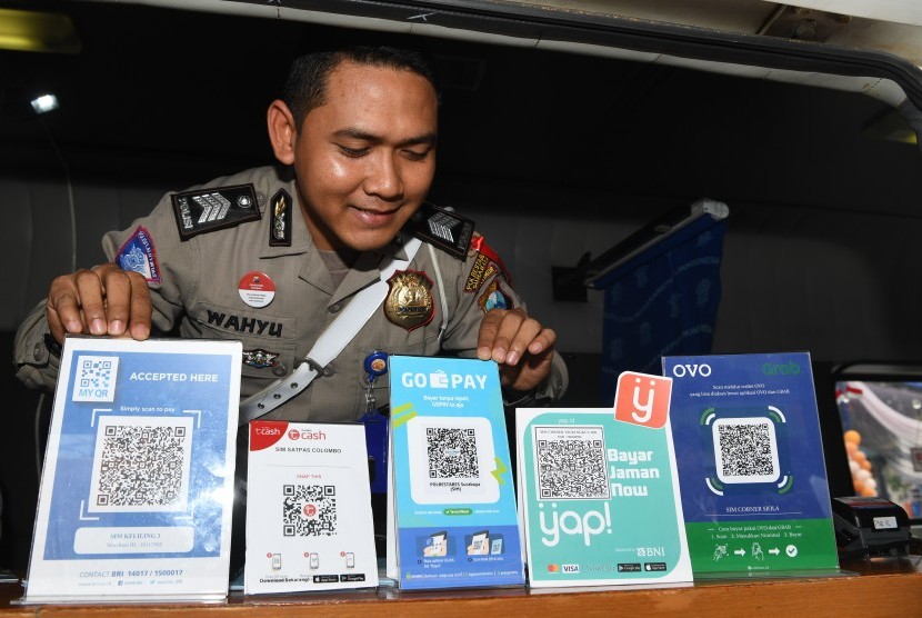 Polisi menunjukkan sejumlah layanan QR code yang terdapat di pelayanan SIM Keliling disela-sela peluncuran program 'Cashless Payment PNBP SIM dan SKCK di Polrestabes Surabaya, Jawa Timur, Sabtu (1/12/2018). 