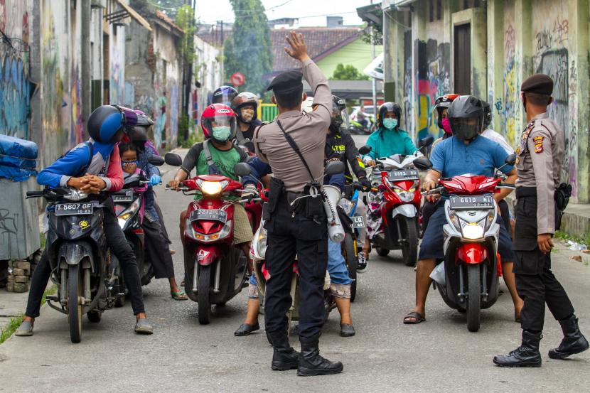 Polisi menyampaikan pemberitahuan penerapan Pembatasan Sosial Berskala Besar (PSBB) kepada pengendara sepeda motor di kawasan Tuparev, Karawang, Jawa Barat. 
