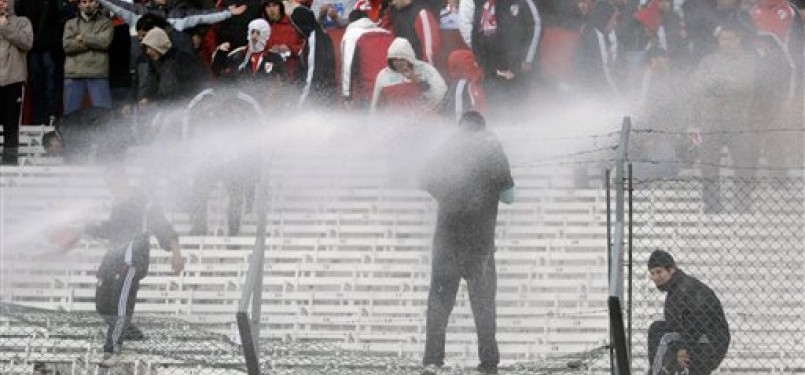 Polisi menyemprotkan air ke arah suporter River Plate yang merusak fasilitas Stadion Monumental usai tim kesayangannya terdegradasi.