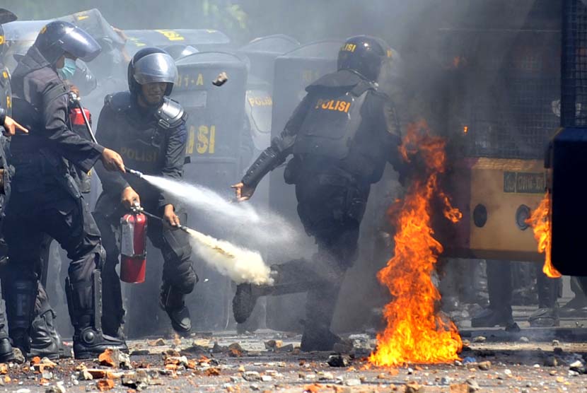  Polisi merusaha memadamkan api dari sebuah bom molotov yang dilemparkan warga saat terjadi bentrokan antara warga dan polisi di Kelurahan Mario Makassar, Sulsel, Senin (21/10).      (Antara/Yusran Uccang)