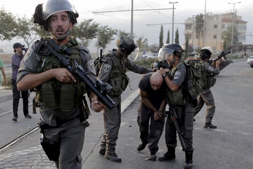 Polisi perbatasan Israel menahan seorang pengunjuk rasa Palestina dalam bentrokan di Shuafat, sebuah daerah pinggiran Arab Yerusalem. 