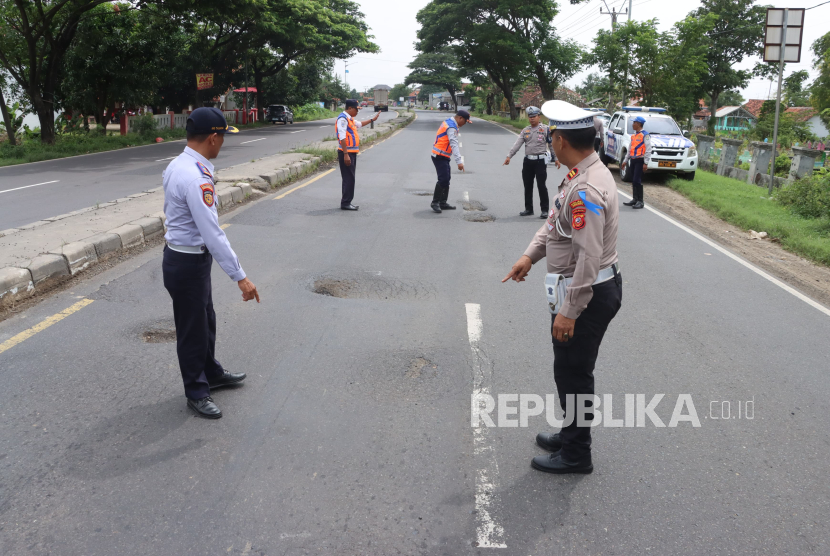 Polisi sedang melakukan pengecekan kondisi jalan berlubang di jalur pantura Indramayu. 