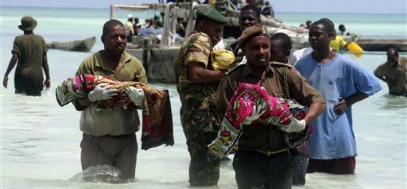 Polisi Tanzania menggendong anak kecil yang tewas tenggelam di Samudera Hindia.