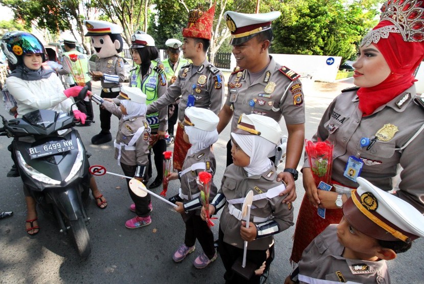 Polisi Wanita (Polwan) cilik membagikan bunga kepada pengendara motor saat Operasi Simpatik Rencong 2016 di jalan Protokol Lhokseumawe, Provinsi Aceh, Jumat (18/3).