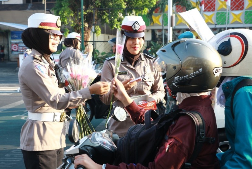 Polisi Wanita (Polwan) dari Polda DI Yogyakarta membagikan bunga dan cokelat kepada pengendara.