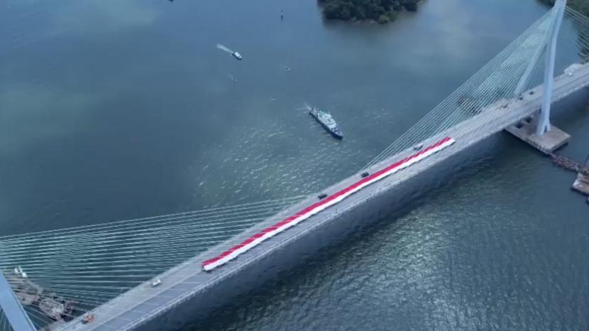 Polri turut menyemarakkan perayaan Hari Kemerdekaan RI ke-78, dengan membentangkan bendera Merah Putih raksasa di sejumlah wilayah di Indonesia. Salah satunya, di Jembatan Pulau Balang, Kalimantan Timur.