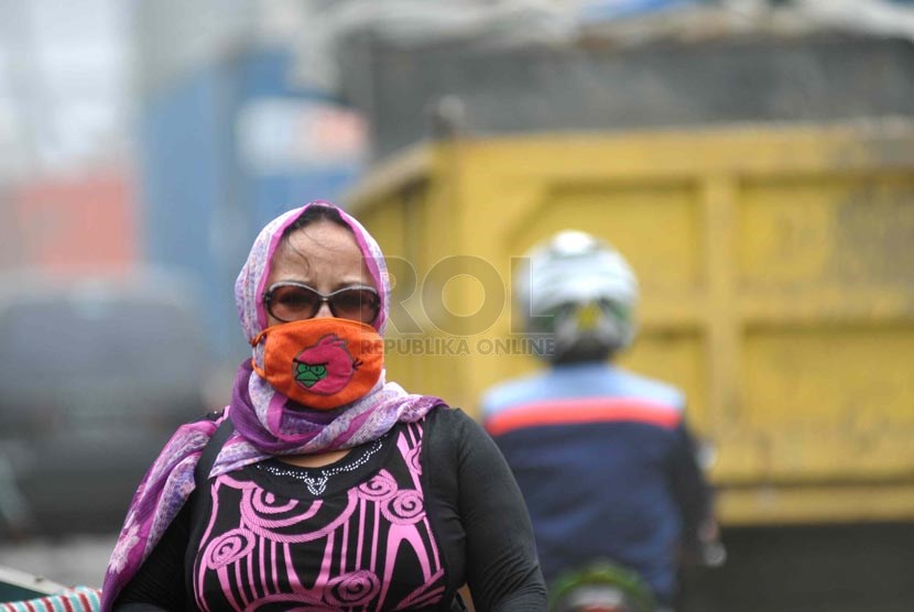 Polus Udara Jalanan. Pejalan kaki menggunakan masker untuk menyaring pekatnya debu di kawasan Koja, Jakarta Utara, Senin (17/3).