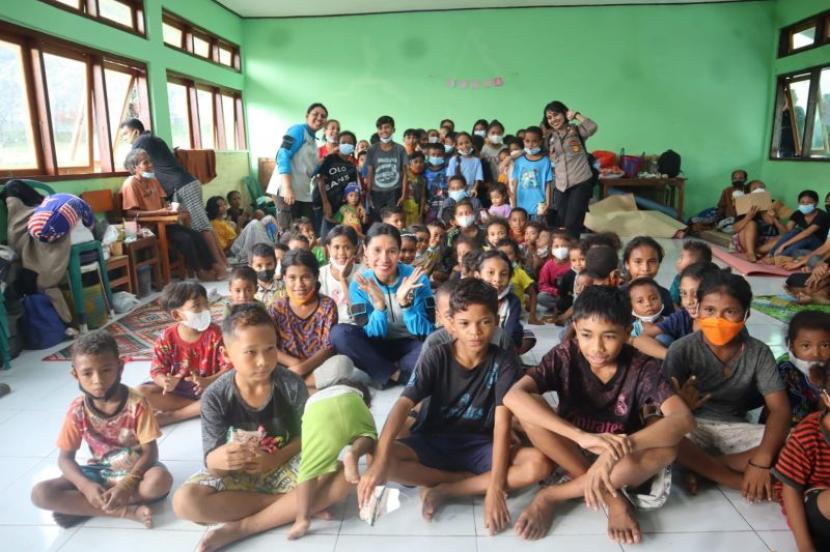 Polwan dari Polres Flores Timur berpose dengan sejumlah anak yang menerima trauma healing di lokasi bencana. 