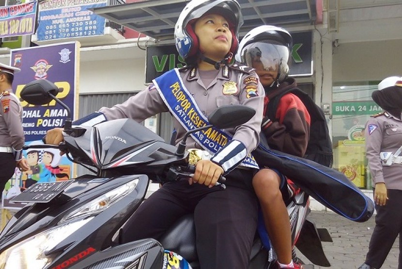 Polwan Satuan Lalu Lintas Polres Semarang bersiap mengantarkan seorang siswa ke sekolahnya di perempatan Sidomulyo, Ungaran, Kabupaten Semarang, Senin (22/8). Langkah tersebut menjadi bagian dari program “Budhal Aman bareng Polisi” (BAP) sebagai edukasi da