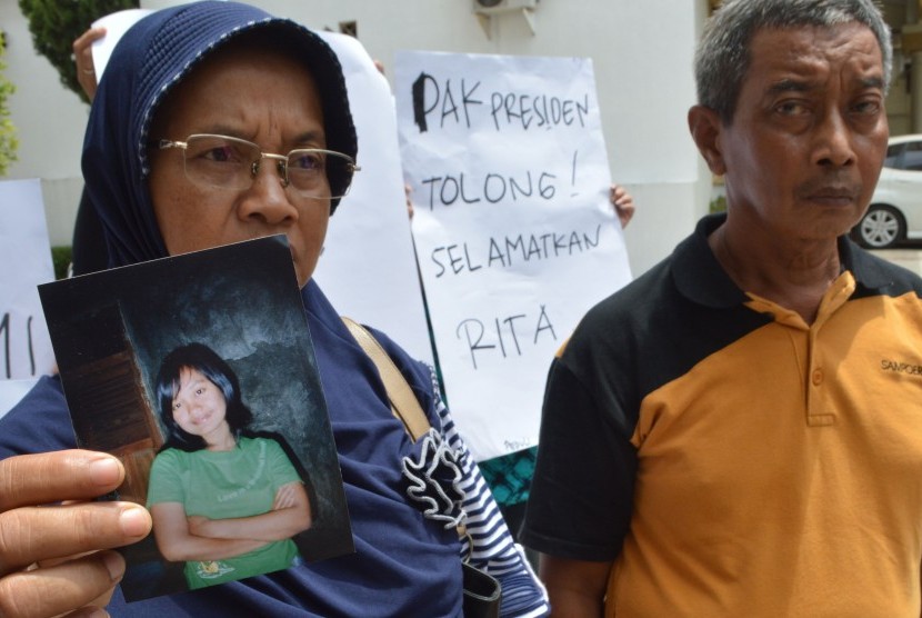 Poniyem (kiri) didampingi suaminya Sarjono menunjukkan foto anaknya, Rita Krisdianti, TKW yang terancam hukuman mati di Malaysia, saat menggelar aksi penolakan hukuman mati bagi Rita Krisdianti di depan Gedung DPRD Kabupaten Ponorogo, Jawa Timur, Senin (25