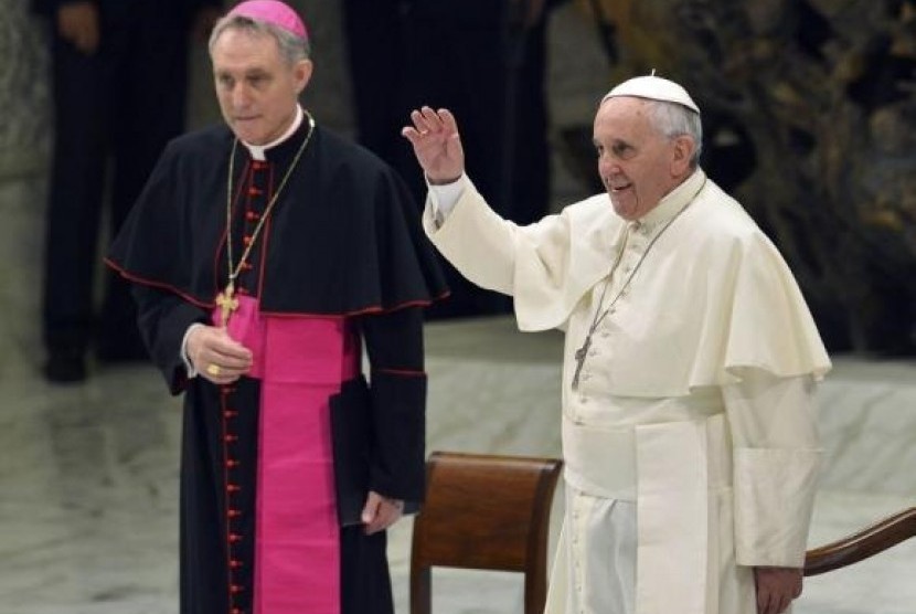 Pope Francis (right), flanked by Archbishop Georg Ganswein, waves as he arrives to lead his Wednesday general audience at the Vatican August 6, 2014.