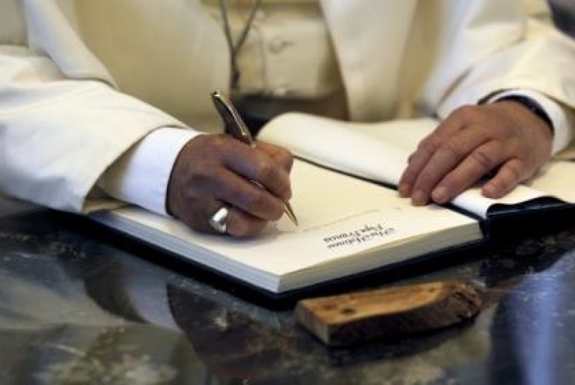 Pope Francis writes a note in the guest book during his visit to the residence of Israel's President Shimon Peres in Jerusalem May 26, 2014.