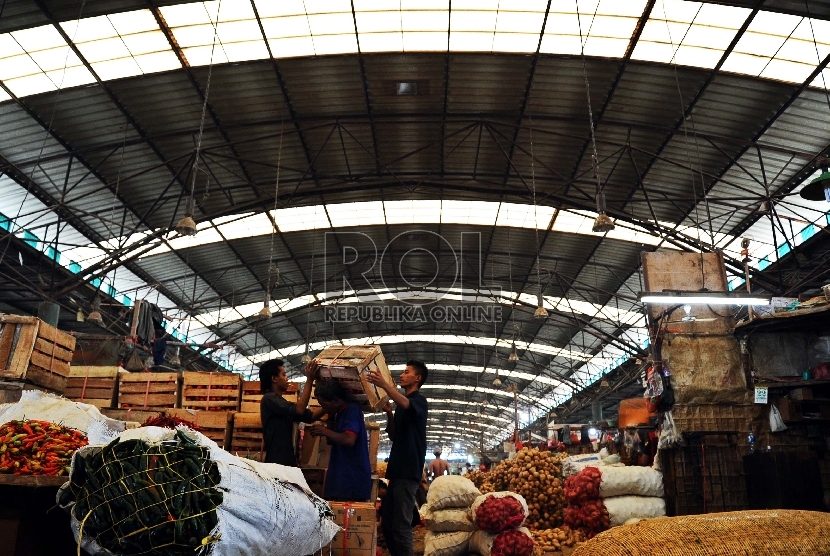 Porter melintas saat memanggul sayur mayur di pasar Induk Kramat Jati, Jakarta, Kamis (23/7).