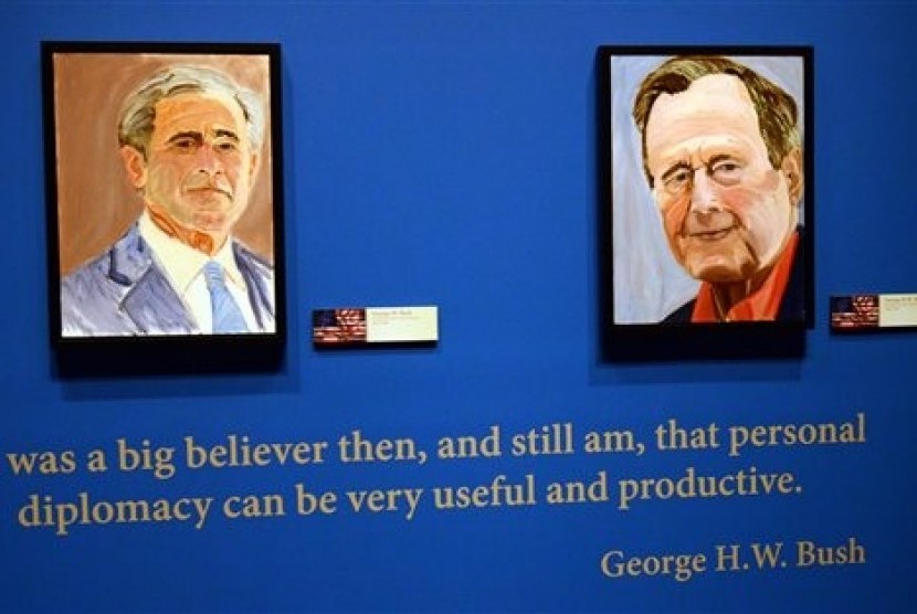 Portraits of former Presidents Goerge W. Bush (left) and his father George H.W. Bush are on display at the George W. Bush Presidential Library and Museum in Dallas, Friday, April 4, 2014.