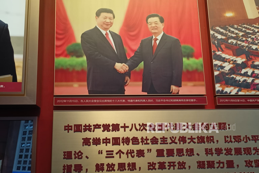 Poster Presiden Xi Jinping bersalaman dengan Presiden Hu Jintao dipajang di Museum Partai Komunis China, Beijing.