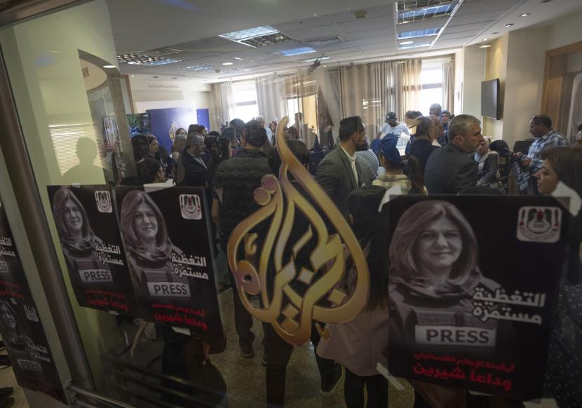  Poster yang memperlihatkan jurnalis Aljazirah Shireen Abu Akleh dan bahasa Arab yang berbunyi, ikon media Palestina, liputan berlanjut, selamat tinggal Shireen, sementara jurnalis dan pelayat berkumpul di kantor saluran Al Jazeera, di kota Ramallah, Tepi Barat, Rabu, 11 Mei 2022. Abu Akleh ditembak dan dibunuh saat meliput serangan Israel di kota Jenin, Tepi Barat yang diduduki, Rabu pagi.