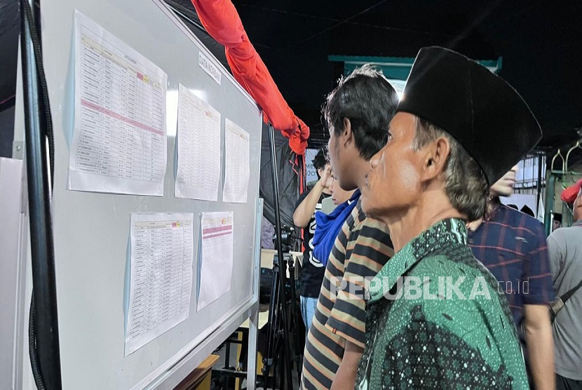 Potret keluarga santri yang melihat daftar nama di papan pengumuman di Posko Pondok Pesantren Al Khoziny, Sepanjang, Sidoarjo. 