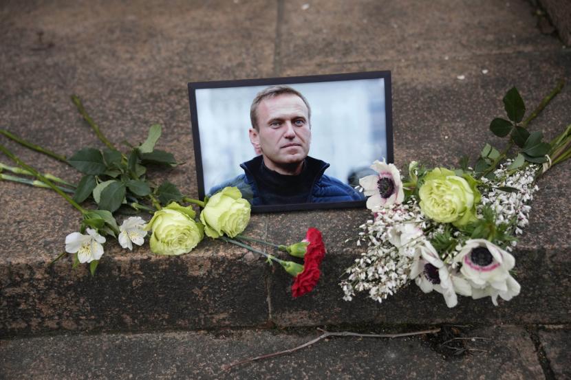 Potret pemimpin oposisi Rusia Alexei Navalny yang dipenjara dan bunga ditempatkan saat orang-orang berunjuk rasa di dekat kedutaan Rusia untuk Prancis, Jumat, 16 Februari 2024 di Paris.