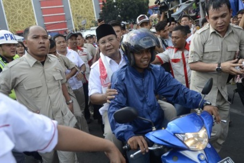 Prabowo Subianto naik sepeda motor saat mengunjungi pasar Tanah Abang, Jakarta, Jumat (20/6). 