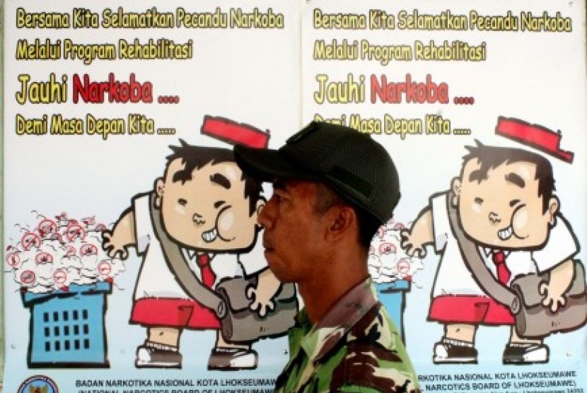 Prajurit Babinsa TNI AD melintas di depan poster seruan?Jauhi Narkoba Demi Masa Depan Kita? di Lhokseumawe, Provinsi Aceh. Kamis (22/10).