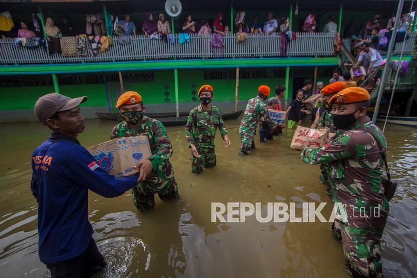 Prajurit Paskhas TNI AU bergotong royong bersama warga mendistribusikan bantuan logistik untuk warga yang terdampak banjir di Desa Lok Buntar, Kabupaten Banjar, Kalimantan Selatan, Selasa (26/1/2021). Korem 101 Antasari bersama Forum Komunitas Hijau (FKH) Banjarmasin dibantu prajurit Paskhas TNI AU dari Bandung dan Jakarta mendistribusikan bantuan logistik untuk korban banjir ke daerah yang sulit di jangkau di Kabupaten Banjar. 