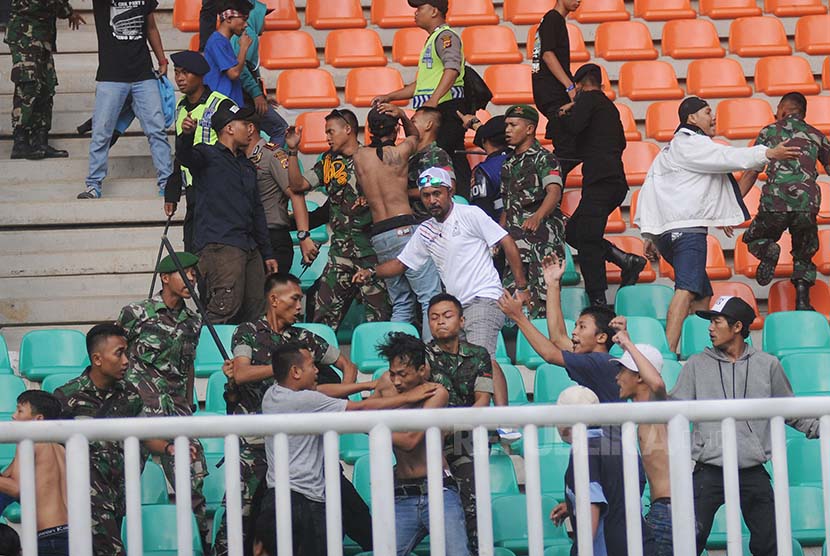 Prajurit TNI AD membubarkan aksi suporter tim sepak bola Jabar yang terlibat bentrok dengan suporter tim sepak bola DKI Jakarta pada babak penyisihan grup A PON XIX di Stadion Pakansari, Cibinong, Bogor, Jawa Barat, Minggu (18/9).