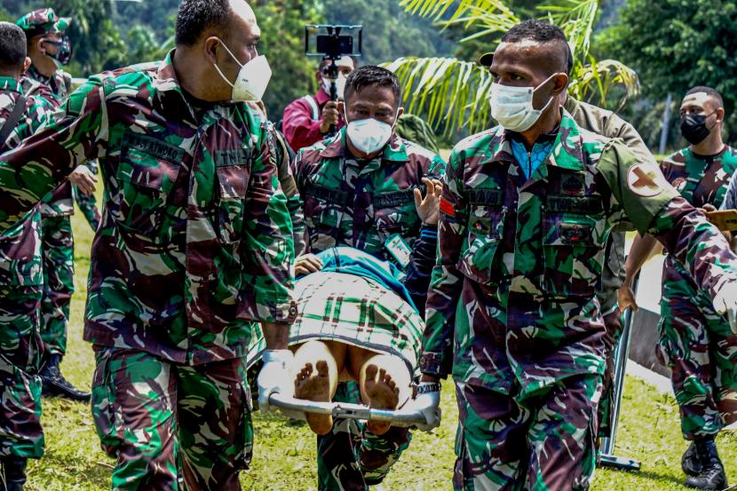 Prajurit TNI AD menggotong tenaga kesehatan (Nakes) korban penyerangan Kelompok Kriminal Bersenjata (KKB) usai dievakuasi menggunakan helikopter milik TNI AD di Lapangan Frans Kaisepo Makodam XVII Cenderawasih, Kota Jayapura.