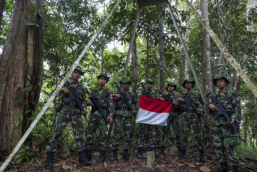 Prajurit Satgas Pengamanan Perbatasan dari Yonif 644/Walet Sakti membentang bendera Merah Putih di lokasi patok negara di hutan perbatasan Indonesia - Malaysia di Entikong, Sanggau, Kalimantan Barat. (Antara/Ismar Patrizki)