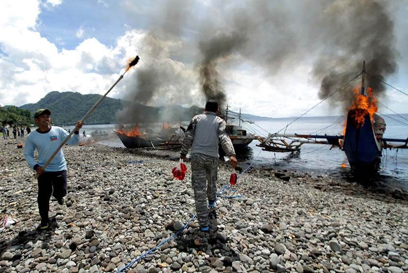 Prajurit TNI AL memusnahkan kapal penangkap ikan ilegal berbendara negara asing dengan cara dibakar di Pangkalan Angkatan Laut (Lanal) Kota Tahuna, Kepulauan Sangihe, Sulawesi Utara, Kamis (31/12). (Antara/Stenly Pontolawokang)