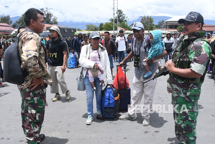 Prajurit TNI berjaga di antara warga yang gagal berangkat untuk mengungsi dengan menumpang pesawat Hercules TNI AU di Bandar Udara Wamena, Papua, Rabu (9/10/2019).