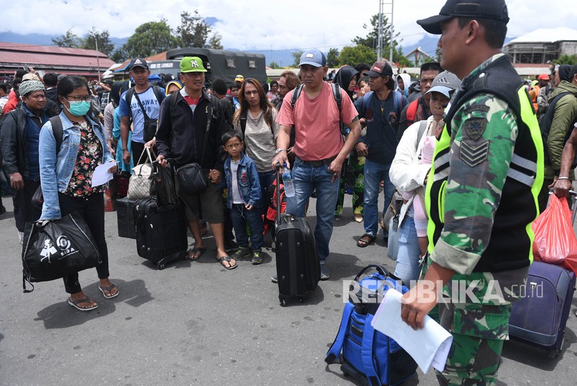 Prajurit TNI berjaga di antara warga yang gagal berangkat untuk mengungsi dengan menumpang pesawat Hercules TNI AU di Bandar Udara Wamena, Papua, Rabu (9/10/2019).