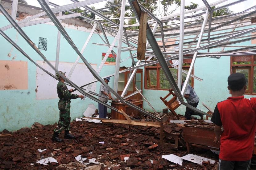 Prajurit TNI bersama warga membersihkan material atap sekolah yang ambruk. (Ilustrasi)