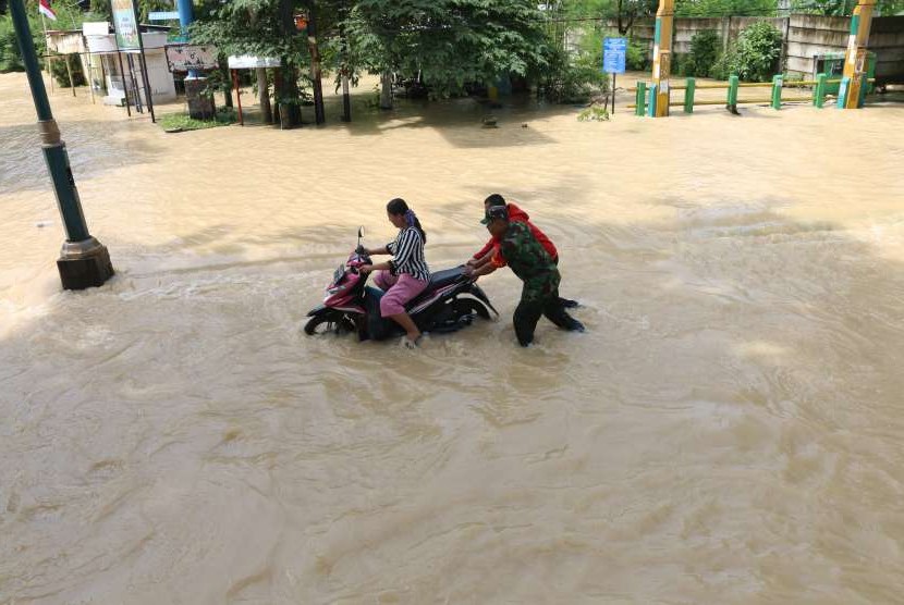 Prajurit TNI bersama warga mendorong sepeda motor warga yang mogok saat melintasi banjir yang merendam kawasan Jalan dr Mansyur, di Medan, Sumatra Utara, Minggu (16/9). 