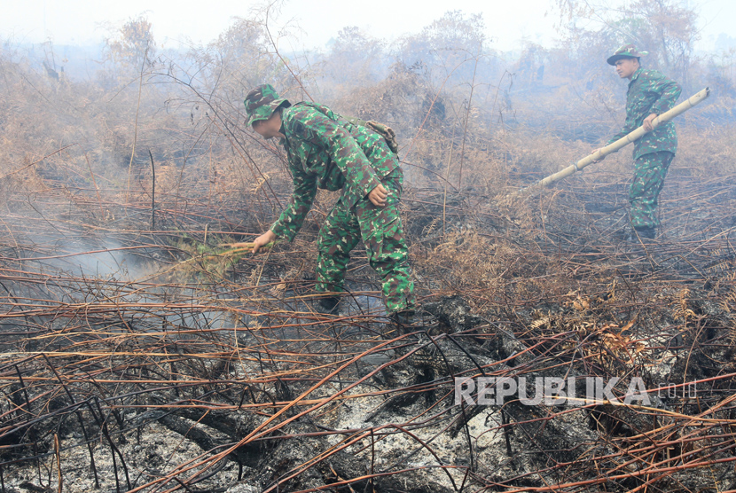 Prajurit TNI dari Kodim 0105 Aceh Barat memadamkan api dengan cara manual di kawasan lahan gambut yang terbakar di Desa Suak Raya, Johan Pahlawan, Aceh Barat, Aceh, Selasa (25/7). 