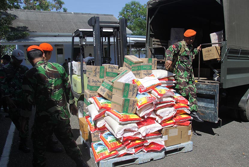 Prajurit TNI membongkar muat logistik bantuan Pemprov Riau dan Pemkot Pekanbaru yang baru tiba di Lanud Sultan Iskandar Muda, Aceh, Besar, Aceh, Kamis (8/12). 